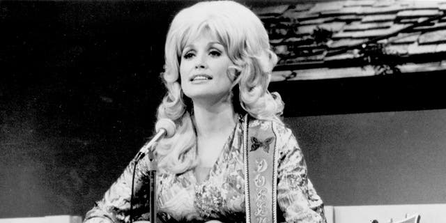Country singer Dolly Parton performs onstage with an acoustic guitar in 1974. 