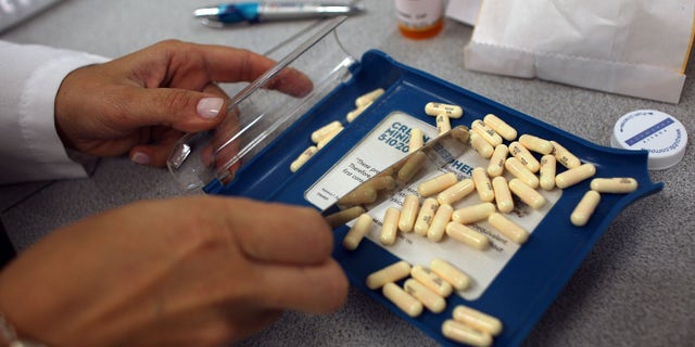 A pharmacy manager counts out the correct number of antibiotic pills to fill a prescription.
