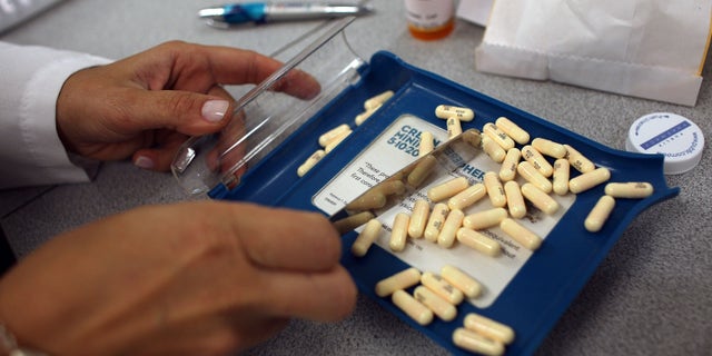 A pharmacy manager counts out the correct number of antibiotic pills to fill a prescription. 