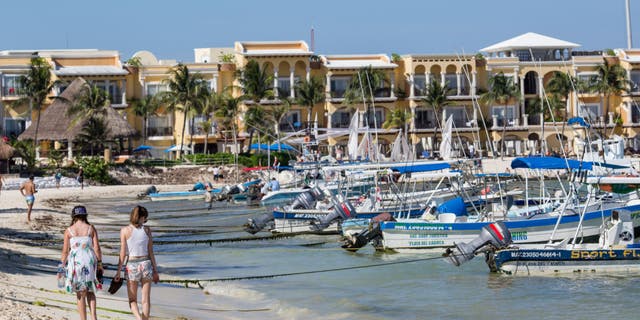 People walk along the beach in Playa del Carmen, Mexico, on Tuesday, July 11, 2017. 