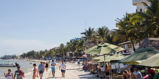 Tourists walk on a beach in Playa del Carmen, Mexico, on Tuesday, July 11, 2017.