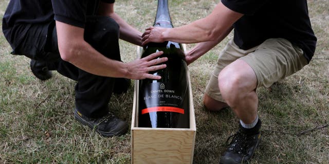 Two men lift a15 litre Nebuchadnezzar bottle of wine.