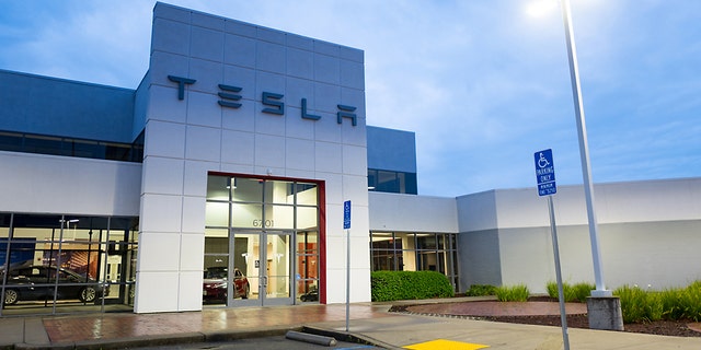 Facade with logo and sign at dusk at the Tesla Motors dealership in Pleasanton, California, March 12, 2018.