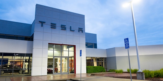 Facade with logo and sign at dusk at the Tesla Motors dealership in Pleasanton, California, March 12, 2018.