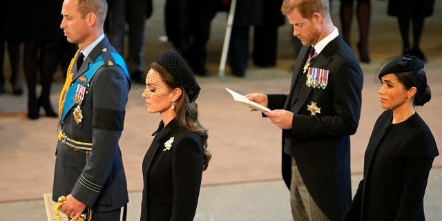 From left to right, Prince William, Prince of Wales, Catherine, Princess of Wales, Prince Harry, Duke of Sussex and Meghan, Duchess of Sussex are seen here inside the Palace of Westminster during the Lying-in State of Queen Elizabeth II on Sept. 14, 2022, in London. It is unclear whether the Duke and Duchess of Sussex will head to the U.K. in May for King Charles III's coronation.