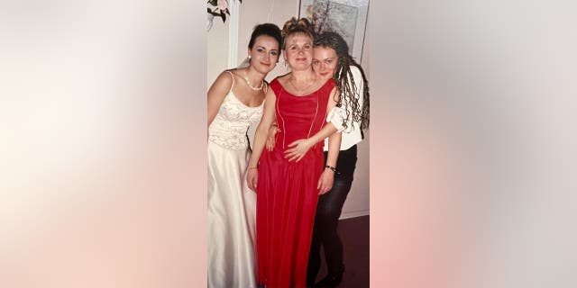 In this handout image provided by the lawyer for Halyna Hutchins' family, Halyna Hutchins, left, is standing next to her mother, Olga Solovey, middle, and sister, Svetlana Zemkno.