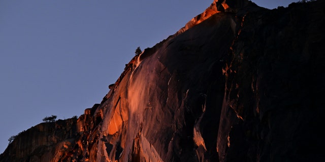 Water flowing off Horsetail Fall glows orange while backlit from the setting sun during the "Firefall" phenomenon in Yosemite National Park, California, on Feb. 15, 2023.