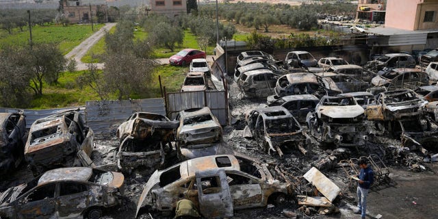 Palestinians inspect scorched cars in a scrapyard, in the town of Hawara, near the West Bank city of Nablus, Monday, Feb. 27, 2023.