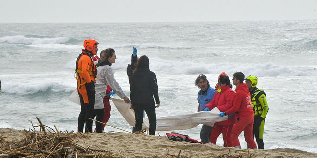 Los equipos de rescate recuperan un cuerpo después de que un bote de migrantes se estrelle en un mar embravecido, en una playa cerca de Cutro, en el sur de Italia, el domingo 26 de febrero de 2023. 