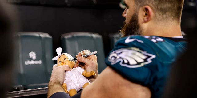 Jason Kelce of the Philadelphia Eagles signs a doll for a fan after an NFL divisional round playoff game against the New York Giants at Lincoln Financial Field on January 21, 2023 in Philadelphia.