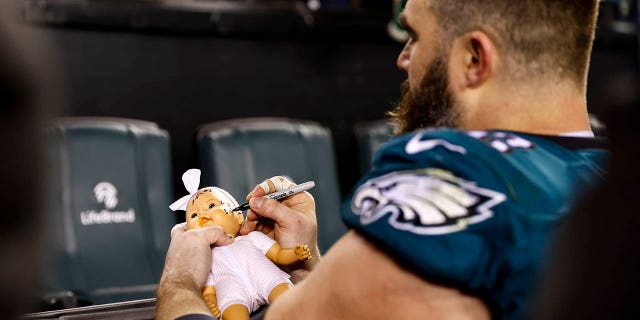 Jason Kelce, de los Philadelphia Eagles, firma un muñeco para un aficionado después de un partido de playoffs de la Ronda Divisional de la NFL contra los New York Giants en el Lincoln Financial Field el 21 de enero de 2023 en Filadelfia.