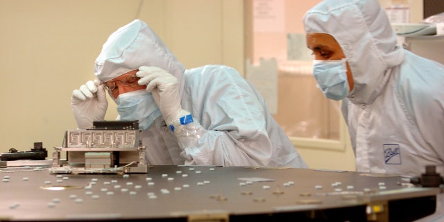 Ball Aerospace & Technologies Corp. engineers Greg Hillen (left) and Raul Martinez work on the back plate for the Schmidt corrector plate, a lens used to correct spherical aberration in a reflecting telescope in NASA's Kepler Mission.