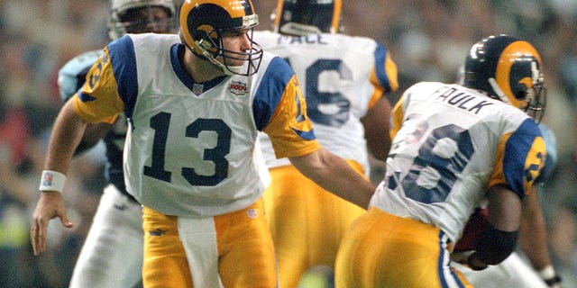 Kurt Warner of the St. Louis Rams passes the ball to Marshall Faulk against the Tennessee Titans during Super Bowl XXXIV at the Georgia Dome on January 30, 2000, in Atlanta.