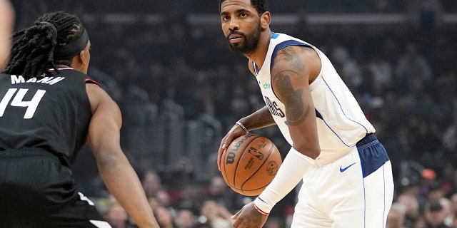 El portero de los Dallas Mavericks, Kyrie Irving, a la derecha, regatea mientras el portero de Los Angeles Clippers, Terance Mann, defiende durante la primera mitad de un partido el 8 de febrero de 2023 en Los Ángeles. 