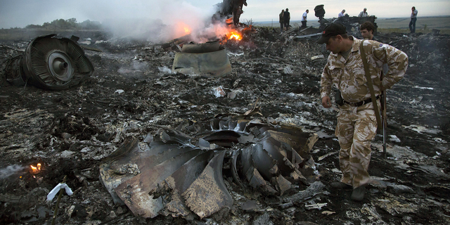 People walk amongst the debris at the crash site of MH17 near the village of Grabovo, Ukraine, on July 17, 2014.