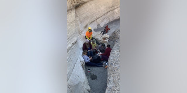 NPS responders assess the Illinois woman (lying down) while her companions support her. The group are seated at the site of the accident in Mosaic Canyon.
