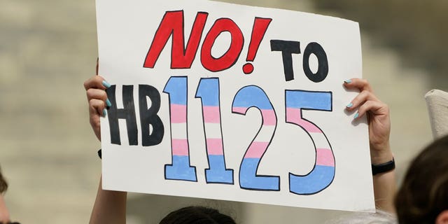 A protester holds a poster calling for lawmakers to vote against House Bill 1125, which would ban gender-affirming care for trans children at the Mississippi Capitol in Jackson, on Feb. 15, 2023. 