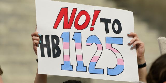 A protester holds a poster calling for lawmakers to vote against House Bill 1125, which would ban gender-affirming care for trans children at the Mississippi Capitol in Jackson Feb. 15, 2023. 