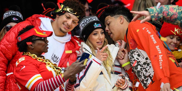 Patrick Mahomes, second from left, looks at a photo with a friend while his wife, Brittany Mahomes, and brother, Jackson Mahomes, right, chat during the Kansas City Chiefs' victory celebration in Kansas City, Mo., Wednesday, Feb. 15, 2023. 