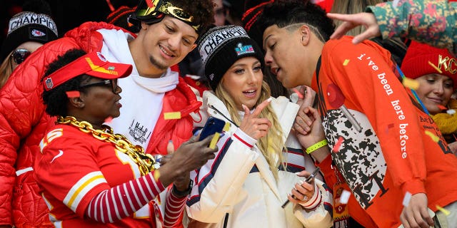 Patrick Mahomes, second from left, looks at a photo with a friend while his wife, Brittany Mahomes, and brother, Jackson Mahomes, right, chat during the Kansas City Chiefs' victory celebration in Kansas City, Mo., Wednesday, Feb. 15, 2023. 