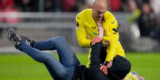 A fan wrestles with Marko Dmitrović of Sevilla FC during a UEFA Europa League match between PSV and Sevilla at Philips Stadium Feb. 23, 2023, in Eindhoven, Netherlands
