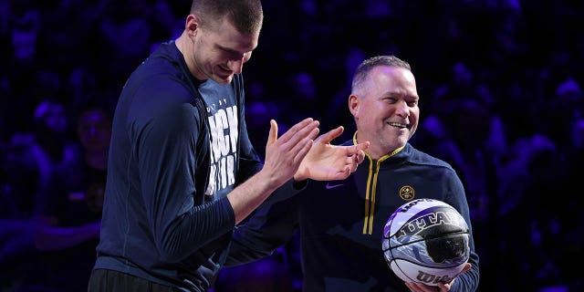 Nikola Jokic, #15, y Michael Malone, de los Denver Nuggets, son honrados por haber sido nombrados para el Juego de Estrellas de la NBA durante el partido contra los Dallas Mavericks en el Ball Arena el 15 de febrero de 2023 en Denver.