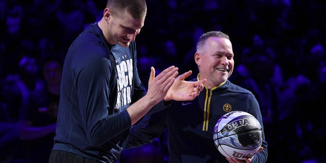 Nikola Jokic, #15, and Michael Malone of the Denver Nuggets are recognized for making the NBA All-Star Game during the game against the Dallas Mavericks at Ball Arena on February 15, 2023 in Denver.