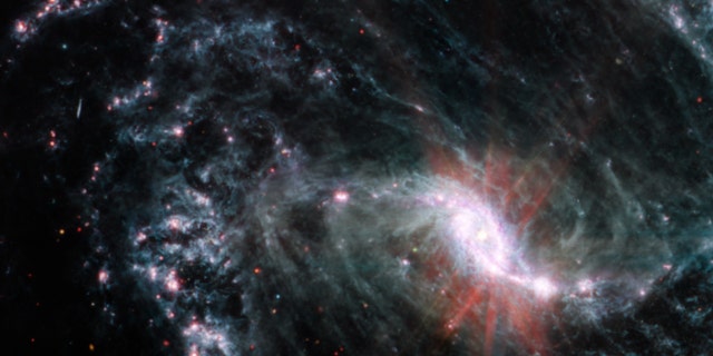 In the MIRI observations of NGC 1365, clumps of dust and gas in the interstellar medium have absorbed the light from forming stars and emitted it back out in the infrared, lighting up an intricate network of cavernous bubbles and filamentary shells influenced by young stars releasing energy into the galaxy’s spiral arms. 