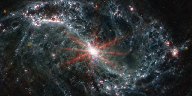 The spiral arms of NGC 7496 are filled with cavernous bubbles and shells overlapping one another in this image from MIRI. These filaments and hollow cavities are evidence of young stars releasing energy and, in some cases, blowing out the gas and dust of the interstellar medium surrounding them.