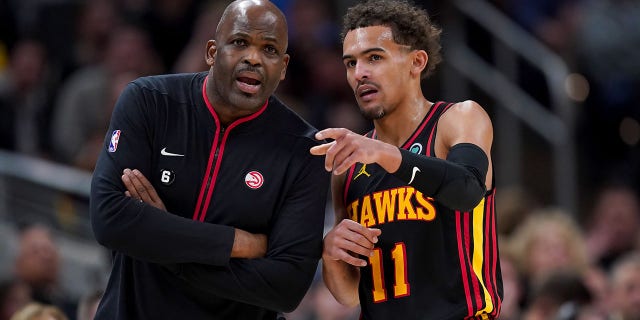 Atlanta Hawks head coach Nate McMillan meets with Trae Young (11) in the fourth quarter against the Indiana Pacers at Gainbridge Fieldhouse on January 13, 2023 in Indianapolis.