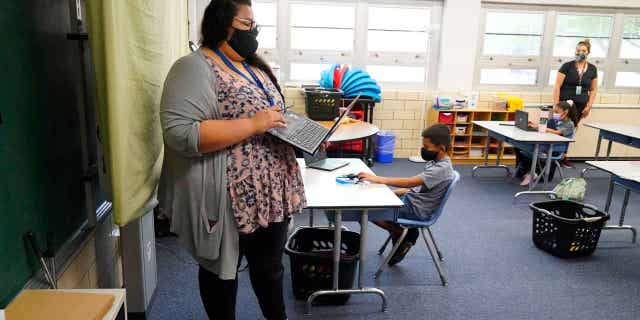 Teacher Jessica Flores directs students as they work on laptops in a classroom in Newlon Elementary School on, Aug. 25, 2020, in Denver, Colorado. Ten states, including Colorado, want to eliminate many of the requirements for teachers to get licensed when they move within the member states.