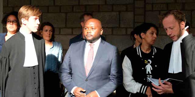 Mpanzu Bamenga, center, stands with his legal team outside a courtroom at The Hague District court in the Netherlands on Sept. 22, 2021. The court banned the Netherlands' military police from using racial profiling to select people for identity checks at borders on Feb. 14, 2023.