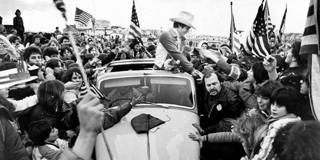Mike Eruzione, captain of the championship US Olympic hockey team, shakes hands with fans on Feb. 25, 1980, in his hometown of Winthrop, Massachusetts, in a Rolls Royce driven by his parents. Police had to put him in his car as thousands descended upon Winthrop to see the champion.