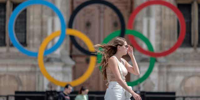 A woman passes by the Olympic rings, at the City Hall in Paris, on July 25, 2022. Latvia is threatening to boycott the 2024 Olympics in Paris if Russian athletes are allowed to compete.