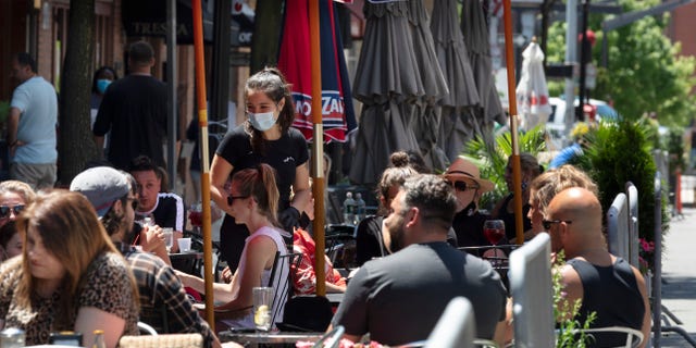 People gather at cafe tables placed in the closed parking lane on Hanover Street in Boston, on June 12, 2020. Boston's outdoor dining program has been made permanent according to Michelle Wu's administration.