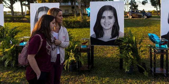 PARKLAND, FL - FEBRUARY 14: People visit a memorial with photos of the 17 people killed in the fifth anniversary Marjory Stoneman Douglas High School mass shooting at Pine Trails Park on February 14, 2023 in Parkland, Florida. On February 14, 2018, 14 students and three staff members were killed in a mass shooting at the school. (Photo by Saul Martinez/Getty Images)