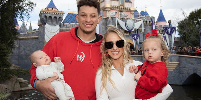 Patrick and Brittney Mahomes pose with their children, Sterling, 1, and Bronze, 11 weeks, at Disneyland Park on February 13, 2023 in Anaheim, California.