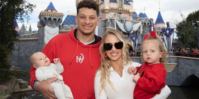 Patrick and Brittney Mahomes pose with their children, Sterling, 1, and Bronze, 11 weeks, at Disneyland Park on February 13, 2023 in Anaheim, California.