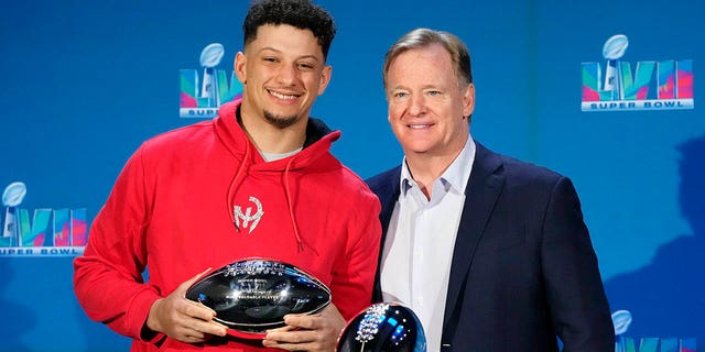 Kansas City Chiefs quarterback Patrick Mahomes, left, holds up the Super Bowl MVP Trophy while standing next to NFL Commissioner Roger Goodell during an NFL Super Bowl football press conference in Phoenix Monday, February 13, 2023.