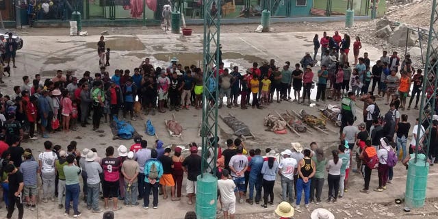 Residents stand around the bodies of persons who perished in recent landslides in Camana, Peru, on Feb. 6, 2023.