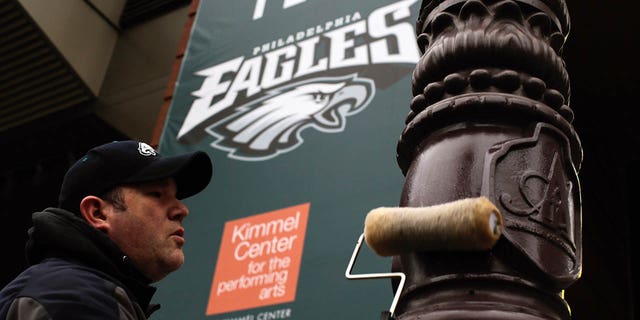 Philadelphia Police officer greases a traffic light pole as security measure for Super Bowl LII fans on February 4, 2018, in Philadelphia, Pennsylvania. The Philadelphia police department is using gear oil to grease up the poles on downtown streets to minimize the damage that fans can do to the city and themselves in the aftermath of the Super Bowl LII that will be played between the New England Patriots and the Philadelphia Eagles.