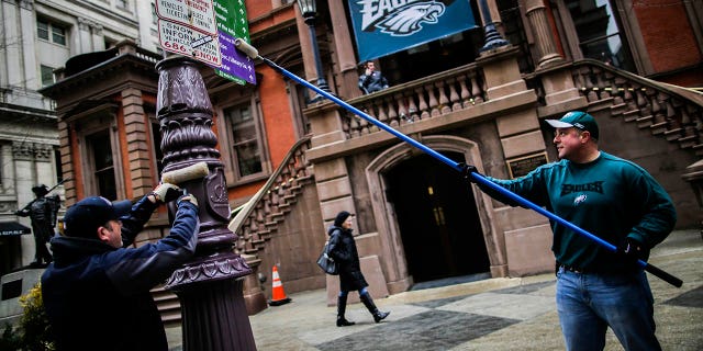 Philadelphia police officers smear traffic light poles as a safety measure for Super Bowl LII fans February 4, 2018 in Philadelphia, Pennsylvania. The Philadelphia Police Department uses gear oil to lubricate the poles on downtown streets to minimize the damage fans can do to the city and themselves after Super Bowl LII, which was played between the New England Patriots and the Philadelphia Eagles is played .