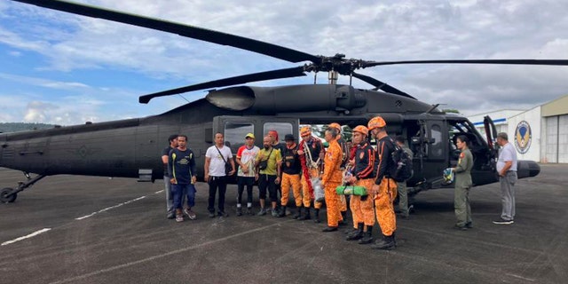 Rescuers stand beside a helicopter as they prepare the search for passengers of a Cessna 340 aircraft at Camalig town, Albay province, Philippines, on Feb. 21, 2023.
