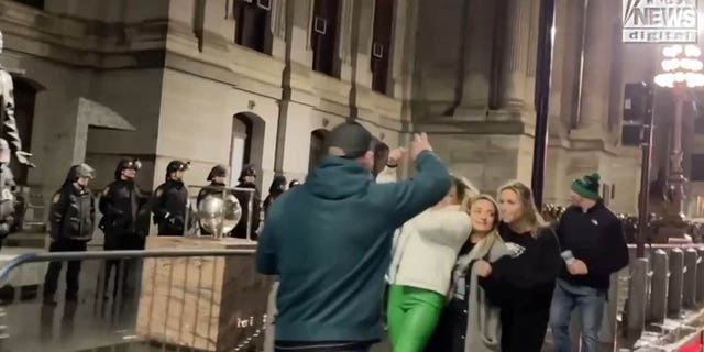 Eagles fans take a photo in front of police.