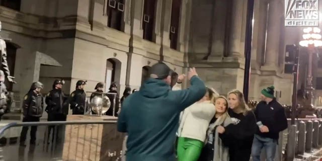 Eagles fans take a photo in front of police.