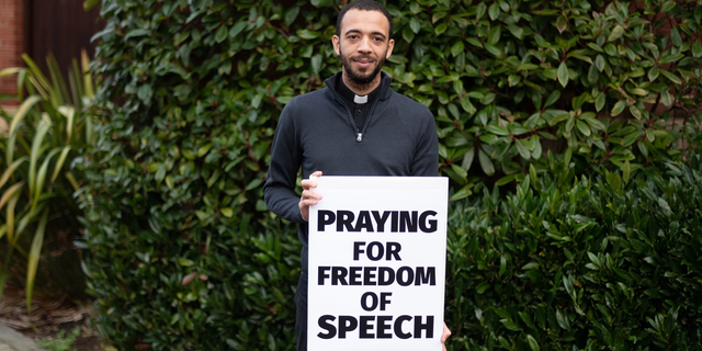 Father Sean Gough holds his "Praying for freedom of speech" sign.