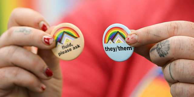 LGBTQ person holds pins about gender pronouns on the University of Wyoming campus on August 13, 2022. 