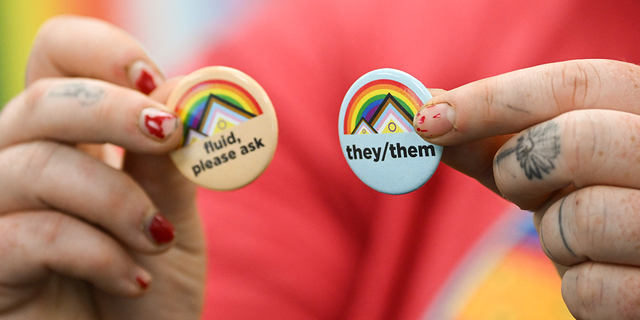 LGBTQ person holds pins about gender pronouns on the University of Wyoming campus on August 13, 2022. 