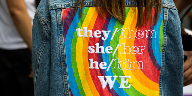 A person wears a gender-neutral pronoun jacket at a ‘Rainbow Runway for Equality.’