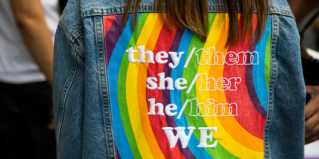 A person wears a gender-neutral pronoun jacket at a ‘Rainbow Runway for Equality.’